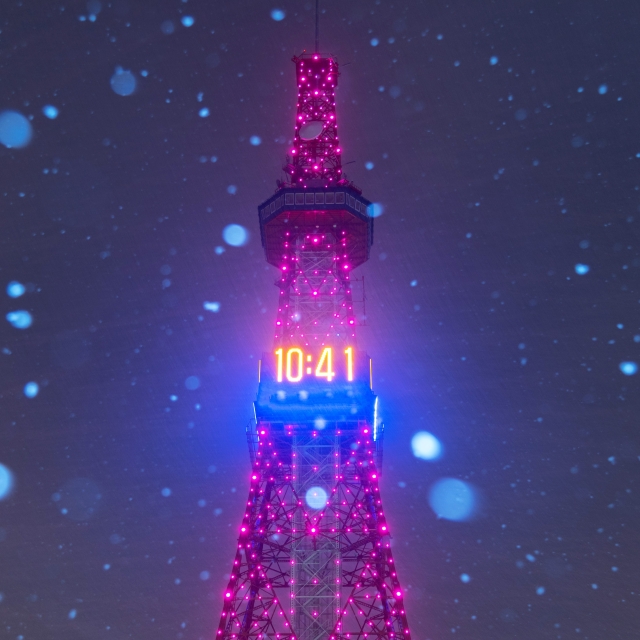 雪が舞う中ピンクにライトアップされたさっぽろテレビ塔