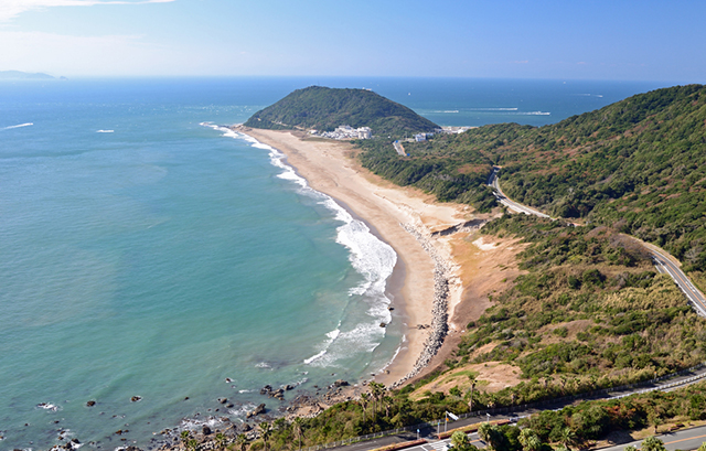 恋路ヶ浜の海岸線と緑豊かな丘陵地帯の風景写真
