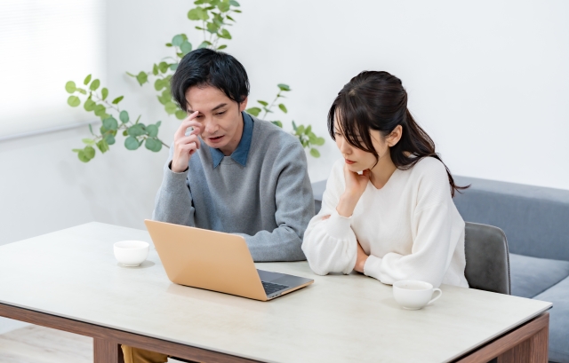 パソコンの前で悩んでいるカップル