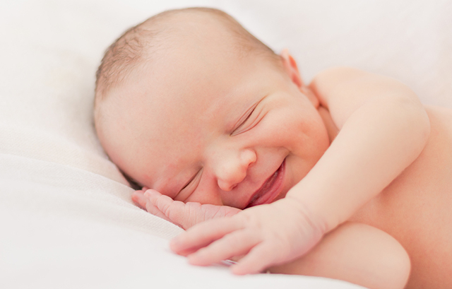 微笑むように眠る乳児