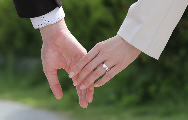 男性の手をとる、婚約指輪と結婚指輪を重ね付けしている女性の手