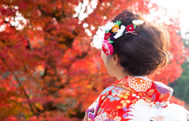 もみじを見上げる着物を着た女性