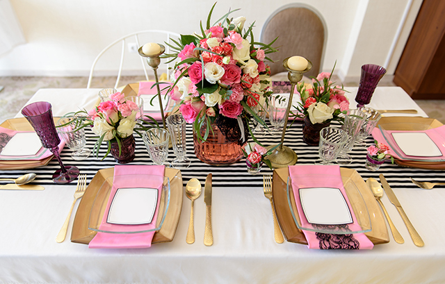 ボーダーのランナーがかけられたテーブルにピンクの装花やナプキンが並ぶ様子