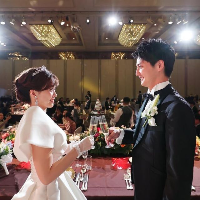 披露宴で新郎新婦が向き合って乾杯している様子