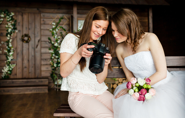 カメラで撮影データを確認する花嫁と女性