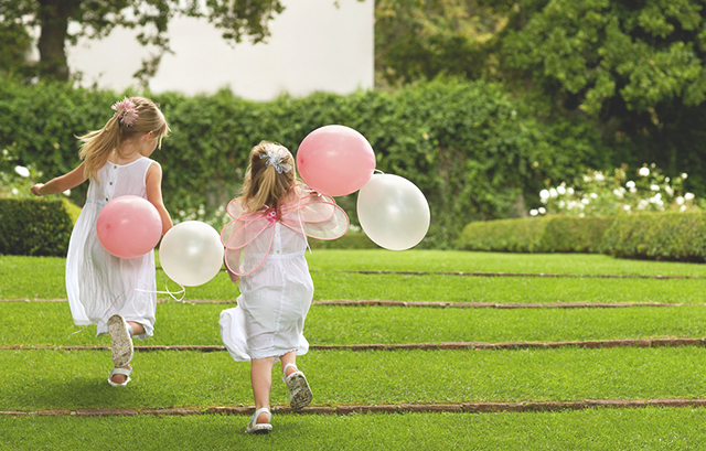風船をもって芝生の上を走る幼い女の子たち