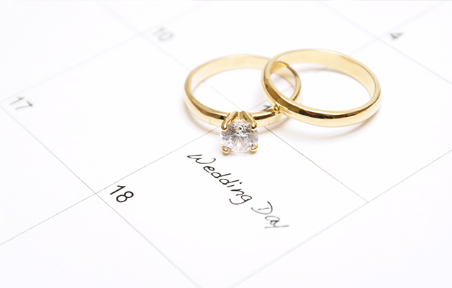 婚約指輪と結婚指輪が置かれた結婚式の日が記されたカレンダー