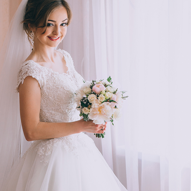窓辺で微笑むウェディングドレス姿の花嫁