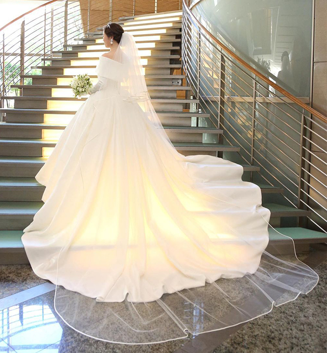 階段に立つ、ロングトレーンよりも長いベールを付けた花嫁