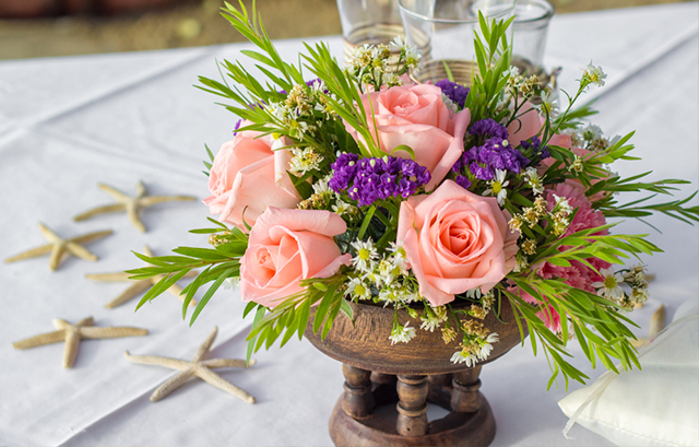 サーモンピンクのバラやグリーンが飾られたテーブル