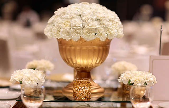白い装花をゴールドの花器で飾った様子