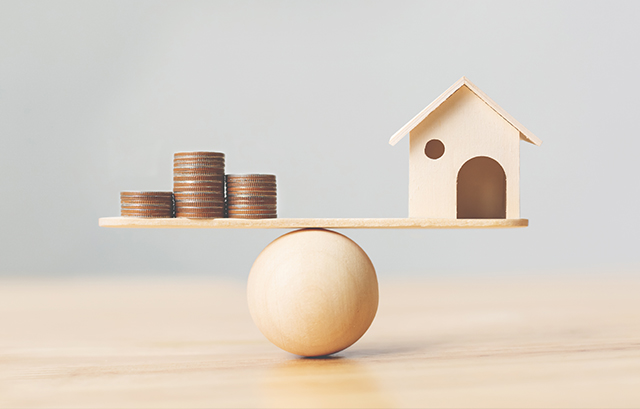 天秤にかけられたお金と家の模型