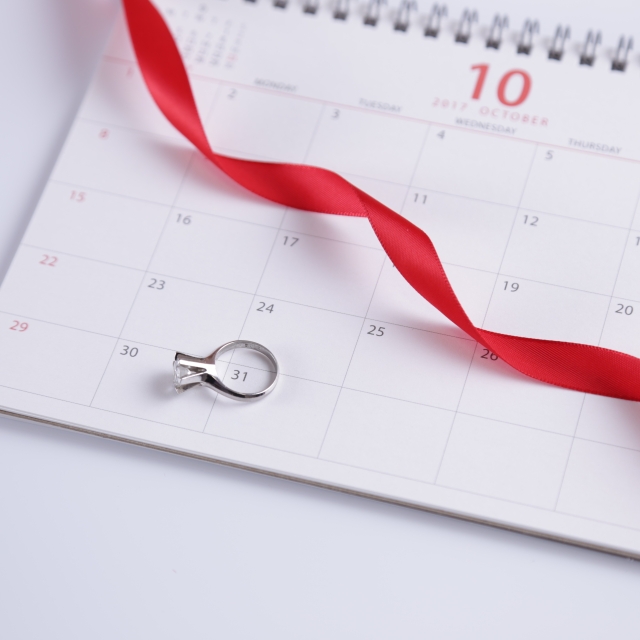 カレンダーの上のある指輪と赤いリボン