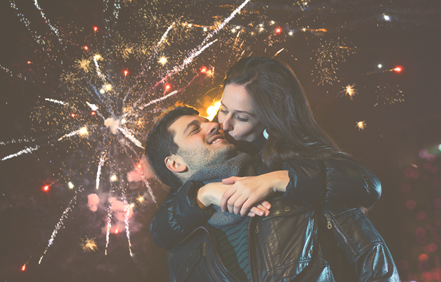 花火を背景に、男性に後ろから抱きつき頬にキスする女性