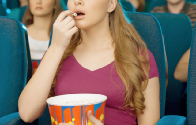 ポップコーンを食べながら映画を見ている女性