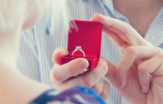 赤い指輪ケースに入った婚約指輪を差し出し、プロポーズする様子