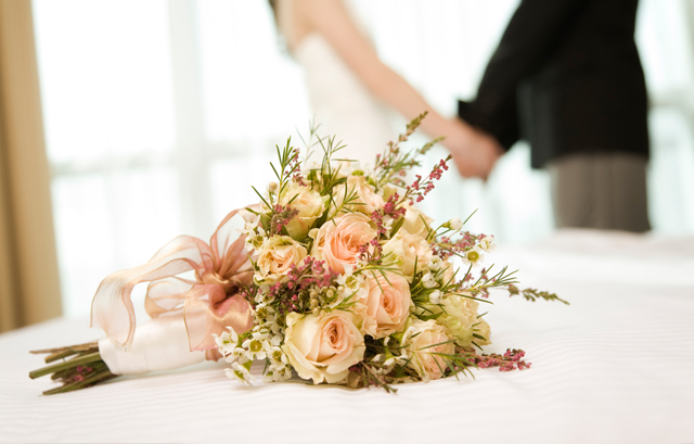 テーブルに置かれた花束とその奥で手を取り合っている男女