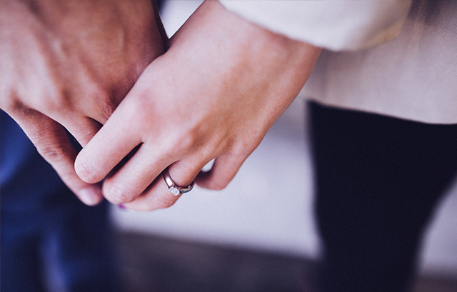 婚約指輪を付けた女性と手を繋ぐ男性