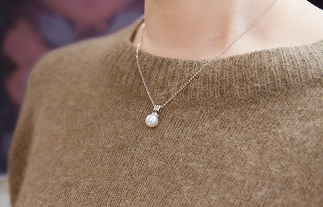 女性がネックレスを付ける様子