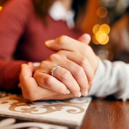 婚約指輪をつけて恋人と手を繋いでいる女性