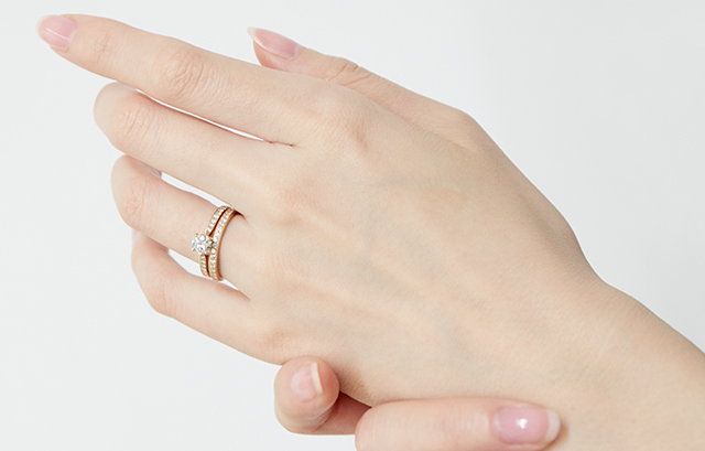 左手薬指に婚約指輪と結婚指輪を付ける女性