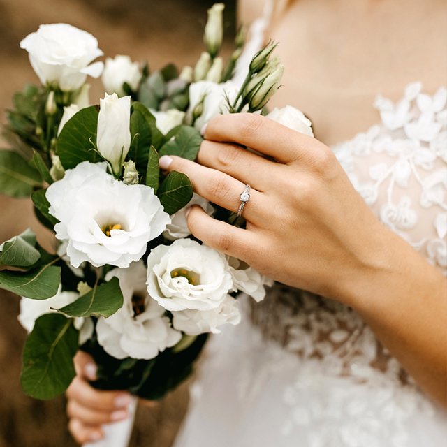 婚約指輪と白いドレスを身に着けてブーケを持っている女性