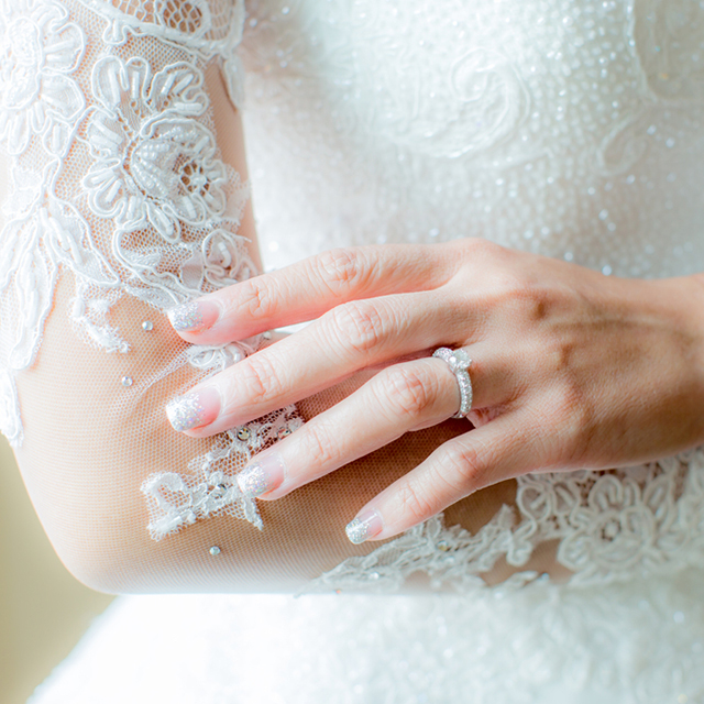 婚約指輪をつけウェディングドレスを着る女性