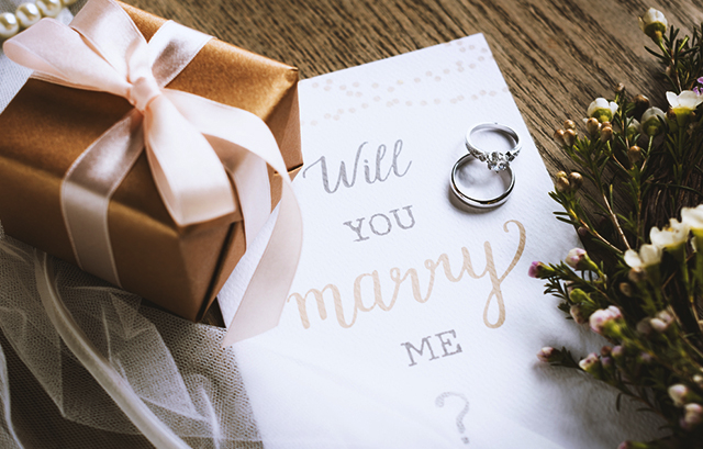 プレゼントボックスと、プロポーズの言葉が書かれたカードの上にある婚約指輪・結婚指輪