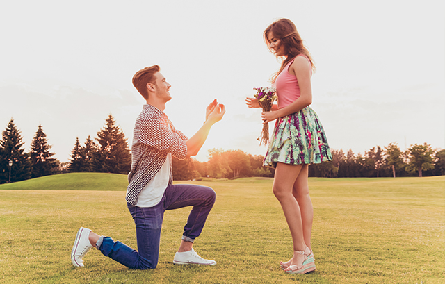夕暮れの公園で片膝をついて婚約指輪を差し出しプロポーズする男性