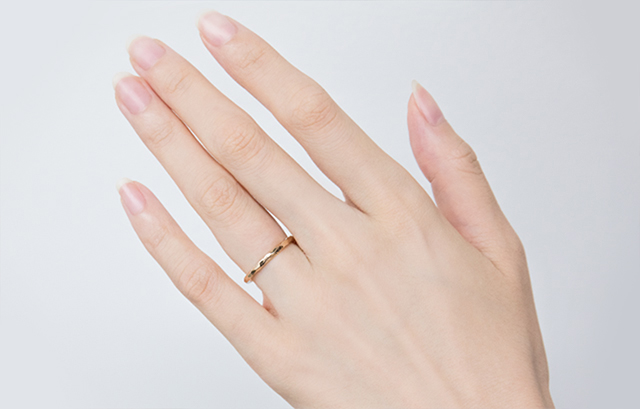 ピンクゴールドの結婚指輪を付ける女性の手