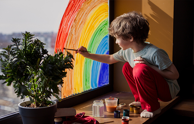 窓に虹の絵を描く子供