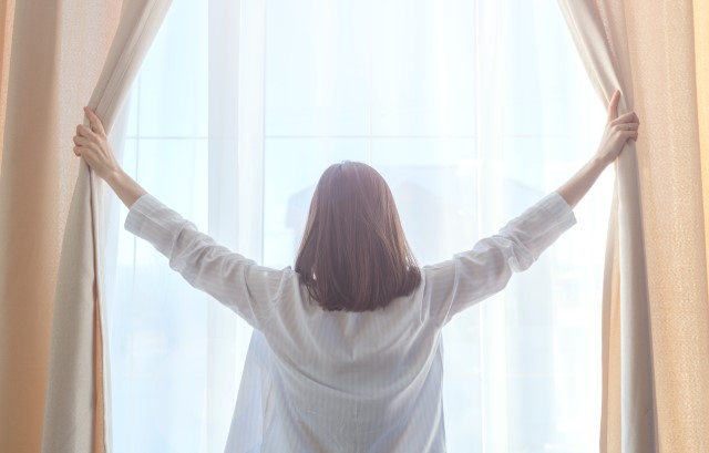 カーテンを開ける女性