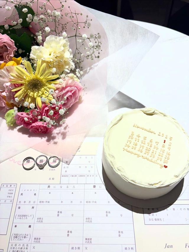 婚姻届、指輪、入籍日とカレンダーが書かれたケーキを収めたショット