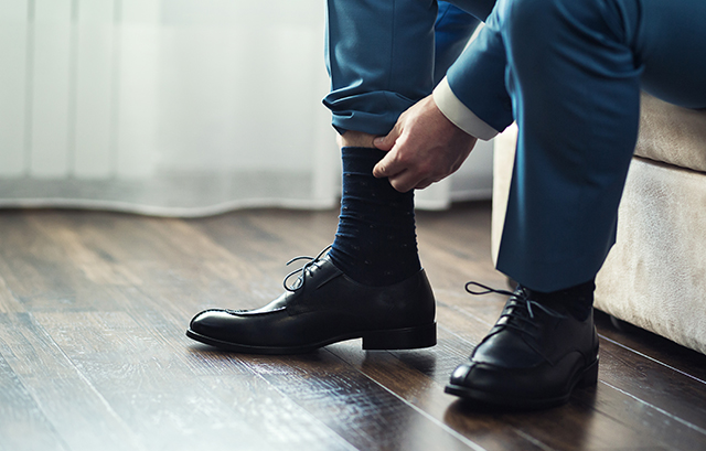 靴下を上げるスーツの男性