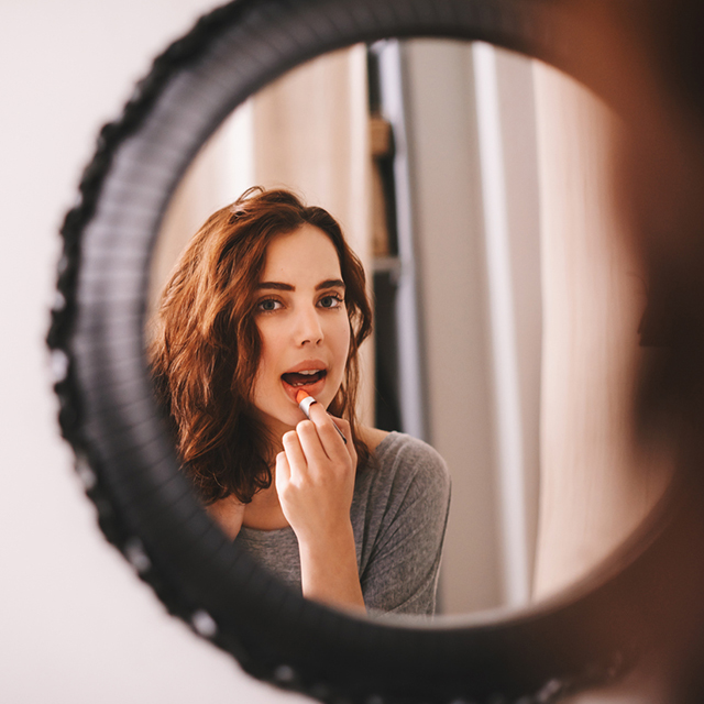 鏡を見ながら口紅を塗る女性