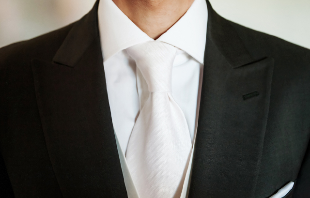 白のネクタイを付けたブラックスーツの男性