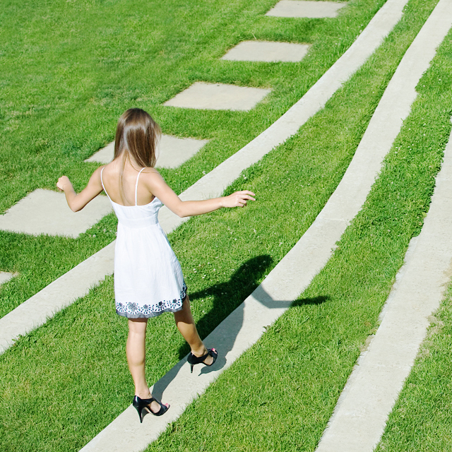 芝生にある細い石の道を歩く女性