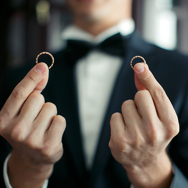 2つの結婚指輪を両手につまんで持つ男性