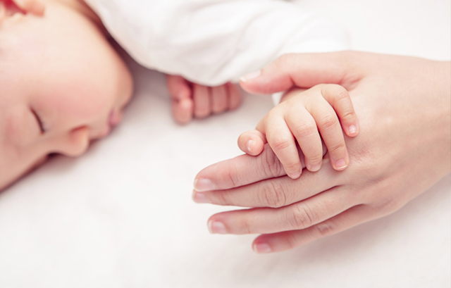 寝ている赤ちゃんと母親の手