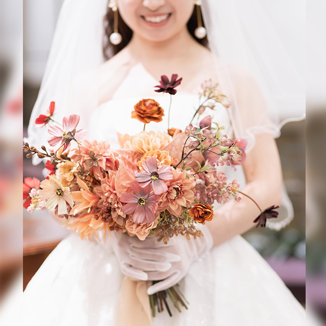 アプリコットカラーのブーケを持つ女性