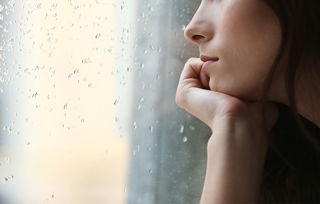 雨降りの外を眺める女性