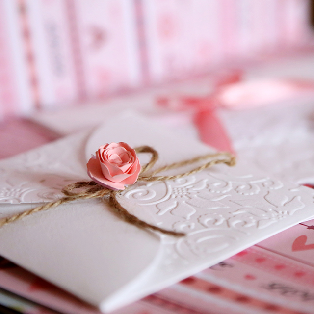 ピンクの紙製のバラが装飾された招待状