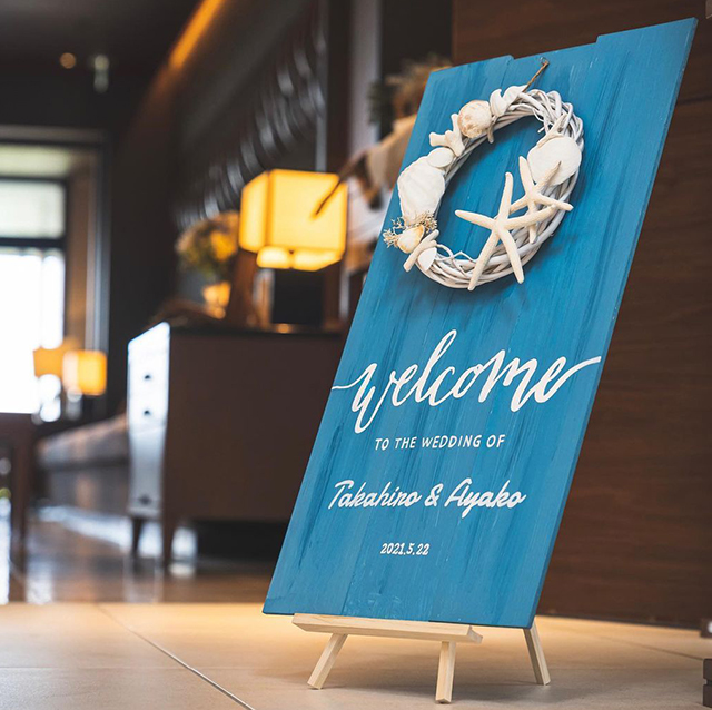 貝殻のリースが付いた青いウェルカムボード