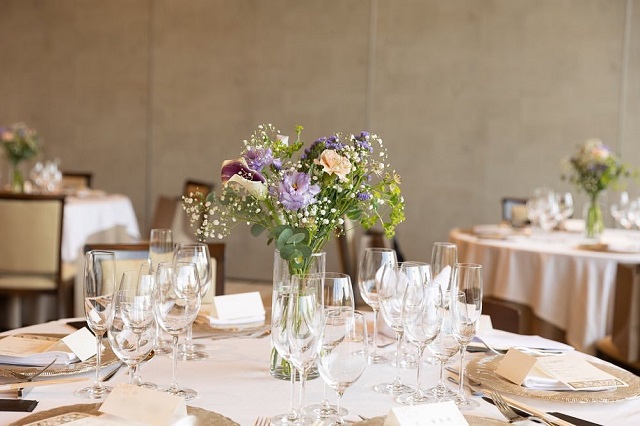 シンプルなゲストテーブルにカスミソウやトルコキキョウで作られた装花が飾ってある様子