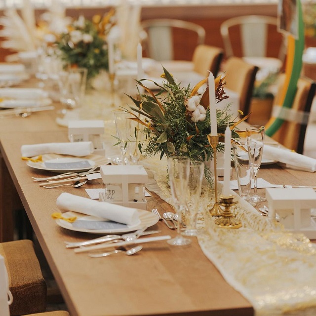 ウッドテーブルにレースのテーブルランナーと装花が飾られた様子