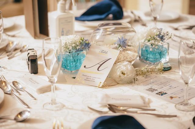 ガラス容器に青いジェルと花が入った飾りが置かれたテーブル