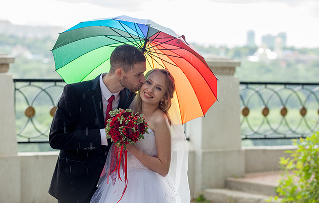 虹色の傘で相合傘をする新郎新婦