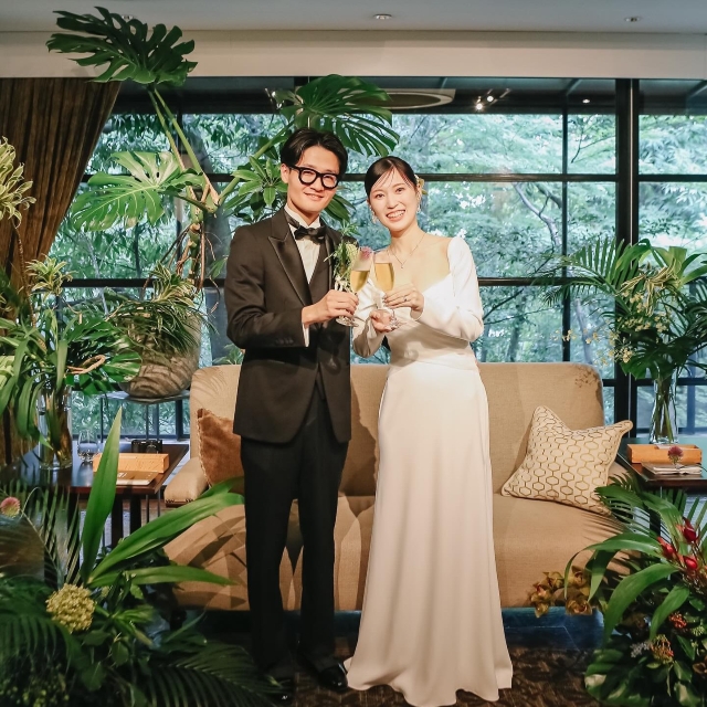 観葉植物で飾り付けた高砂に並んで立つ新郎新婦