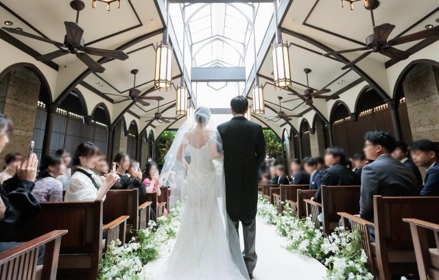 両脇に花が飾られたバージンロードを歩く新郎新婦