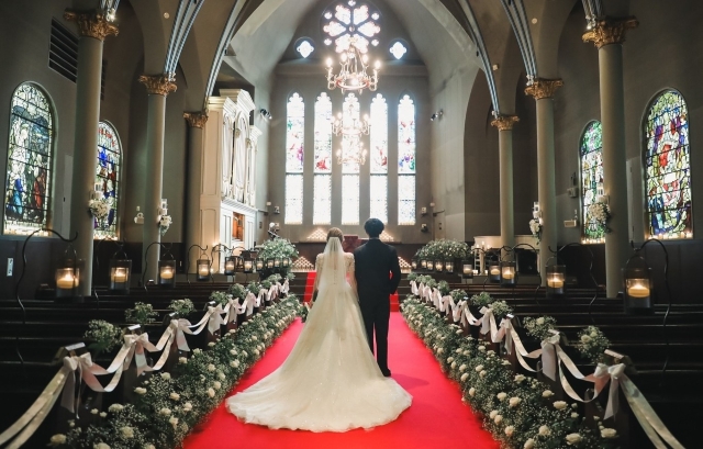 両脇に花が飾られた赤いバージンロードを歩く新郎新婦